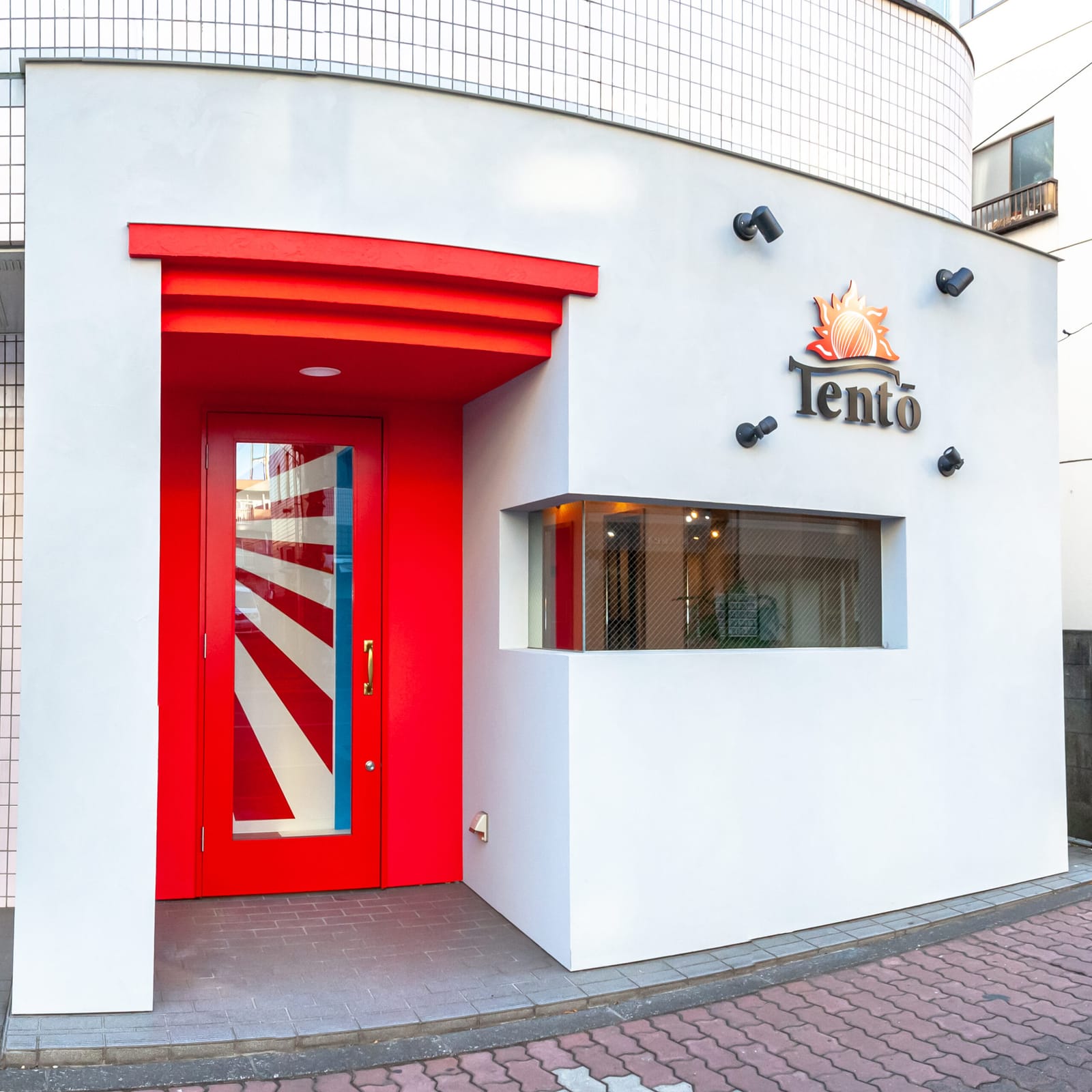 赤い扉と太陽の看板が目印の店の入口